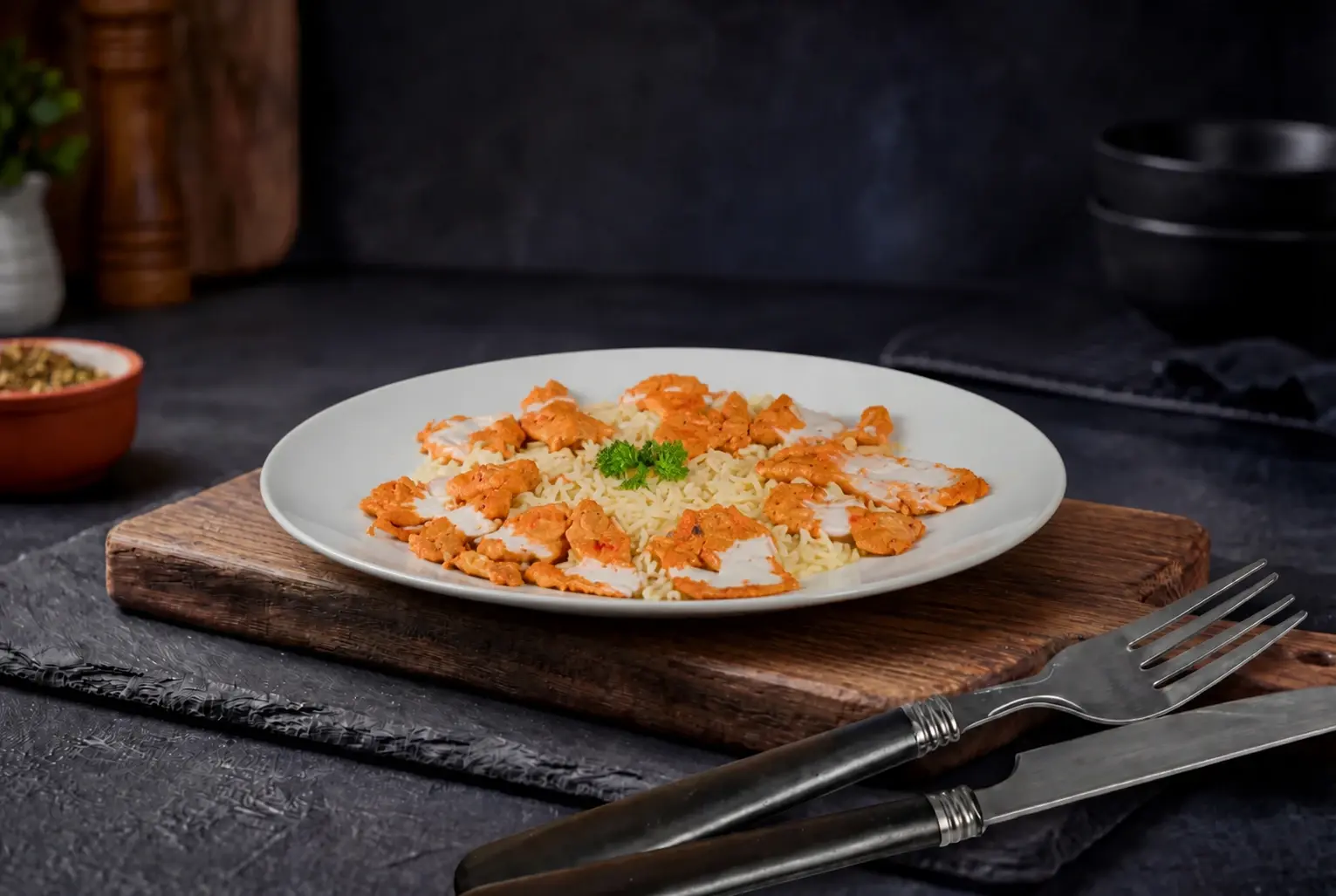Sliced chicken in creamy sauce served over white rice, garnished with parsley